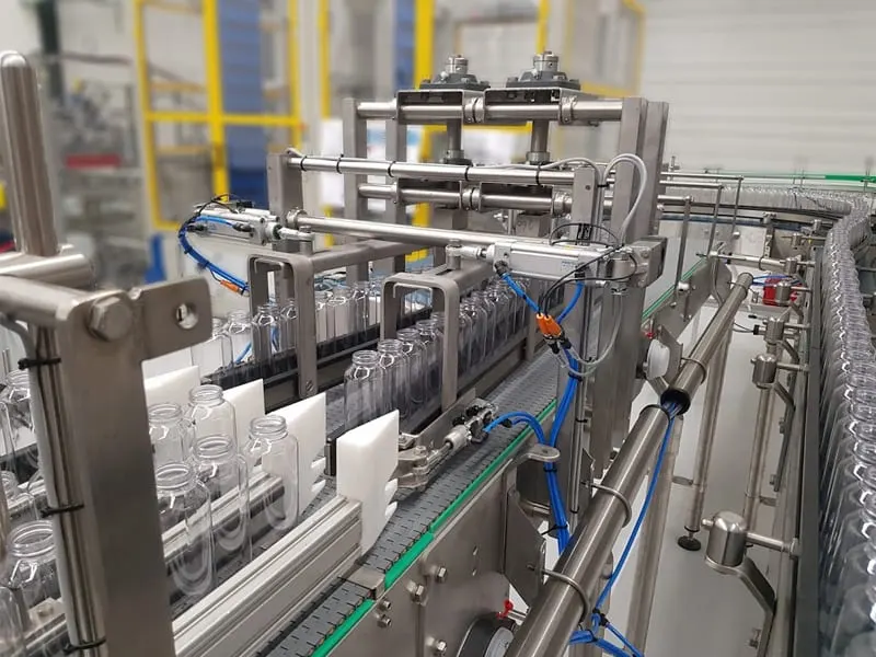 Geautomatiseerde productielijn met kleine lege flessen op lopende band.