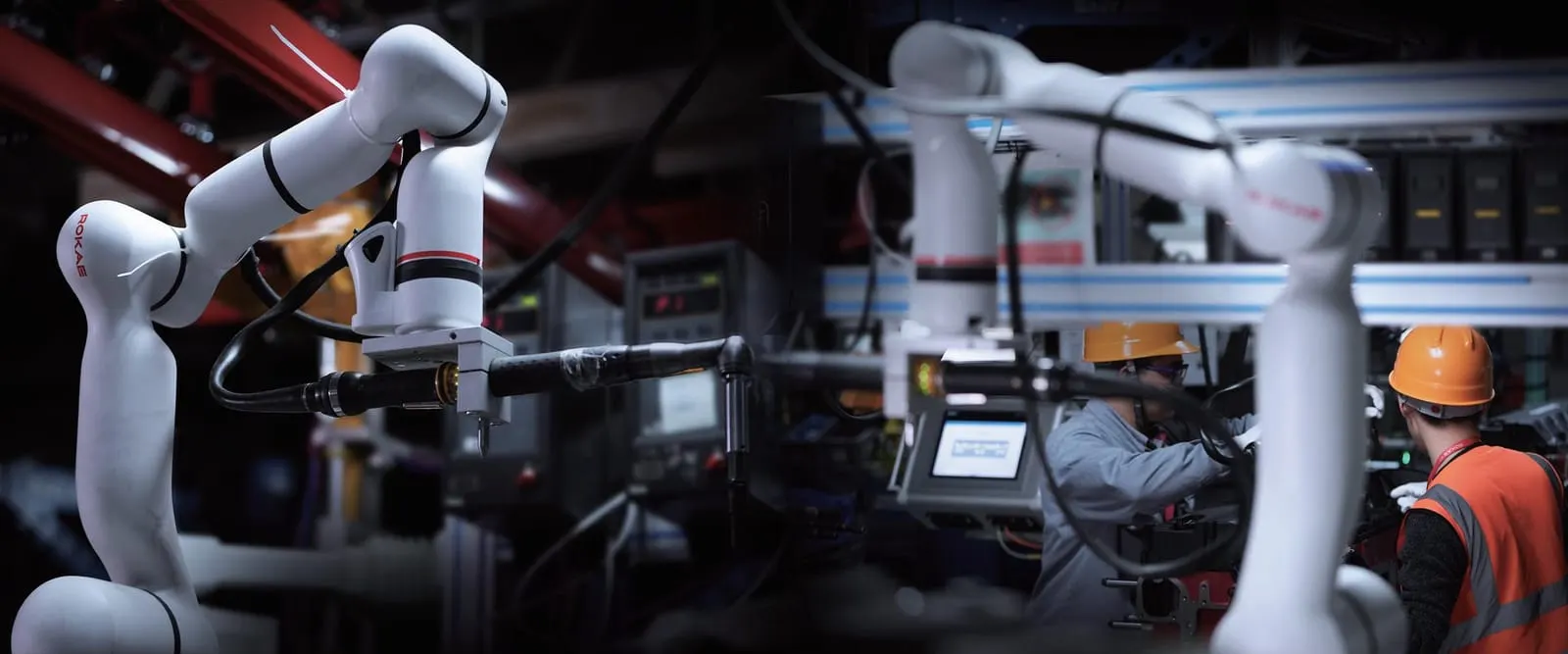 Cobots aan het werk naast operators, die de robot bedienen met een tablet.
